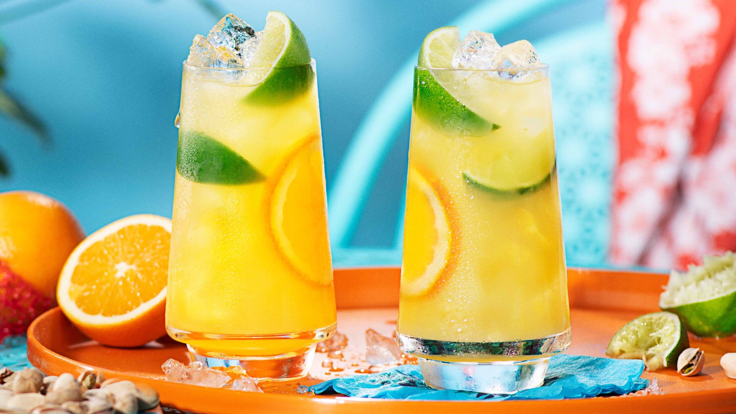 Two malibu and orange juice cocktails in a highball glass, on an orange serving tray