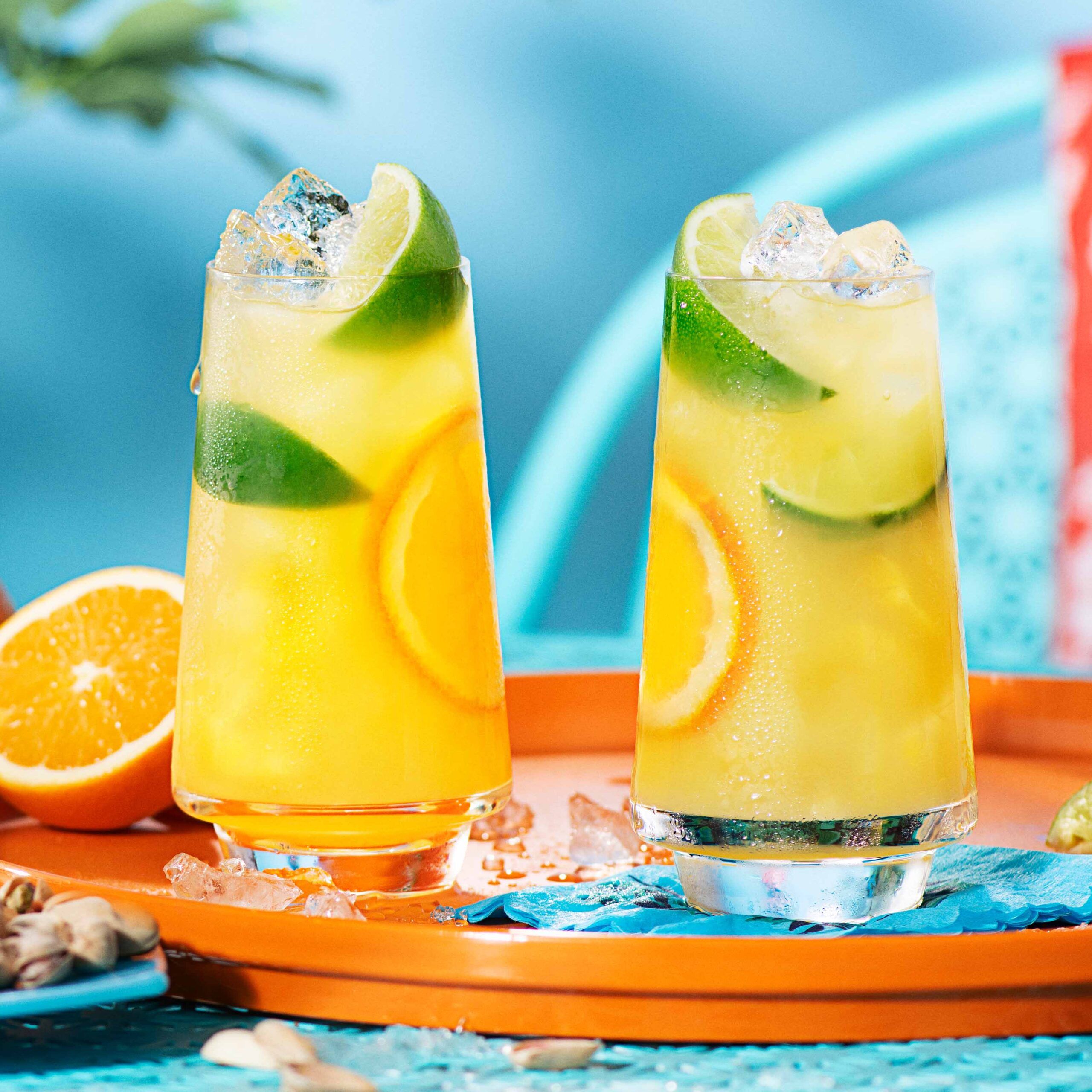 Two malibu and orange juice cocktails in a highball glass, on an orange serving tray