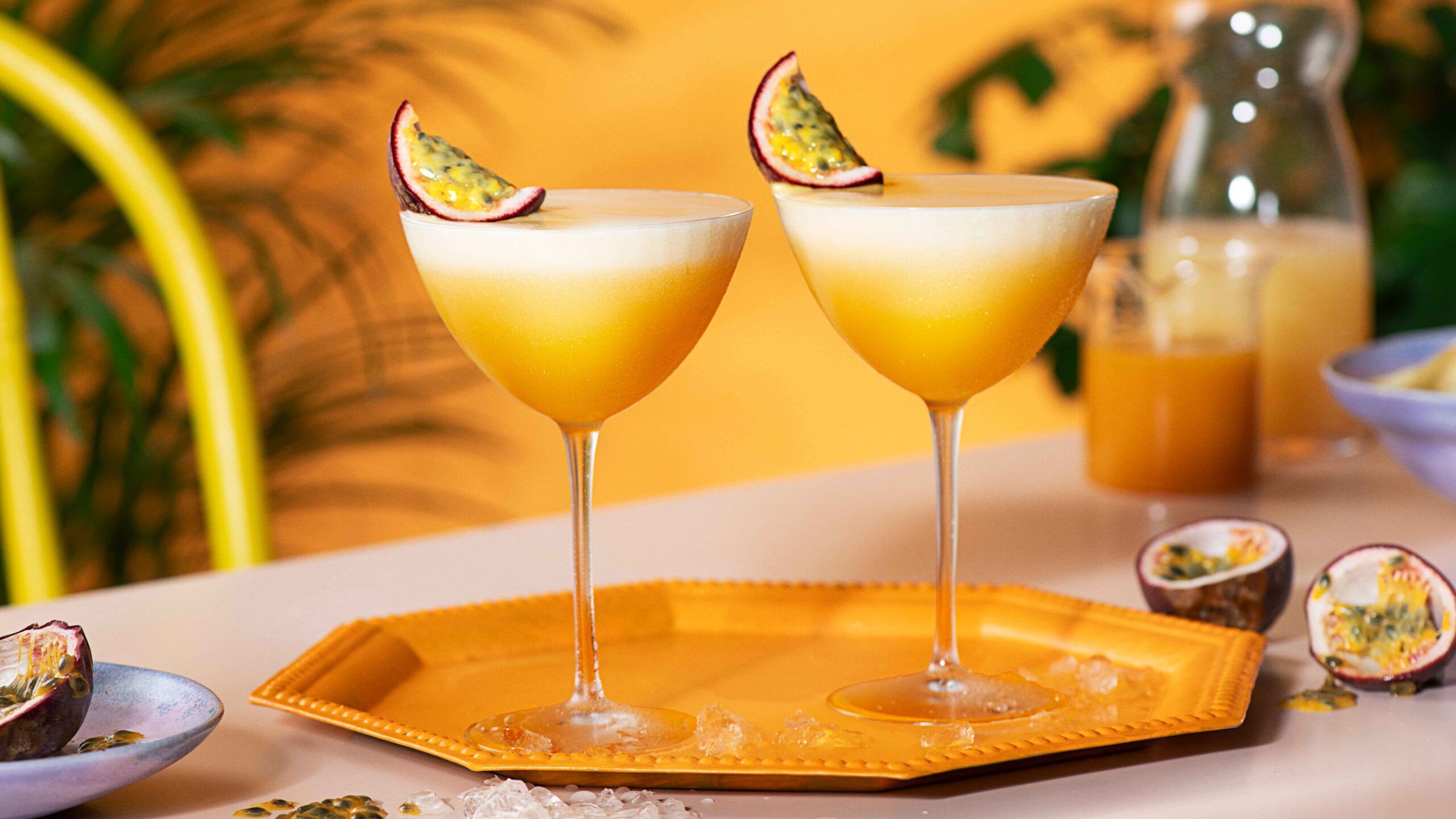 Two porn star martinis on a table against an orange background