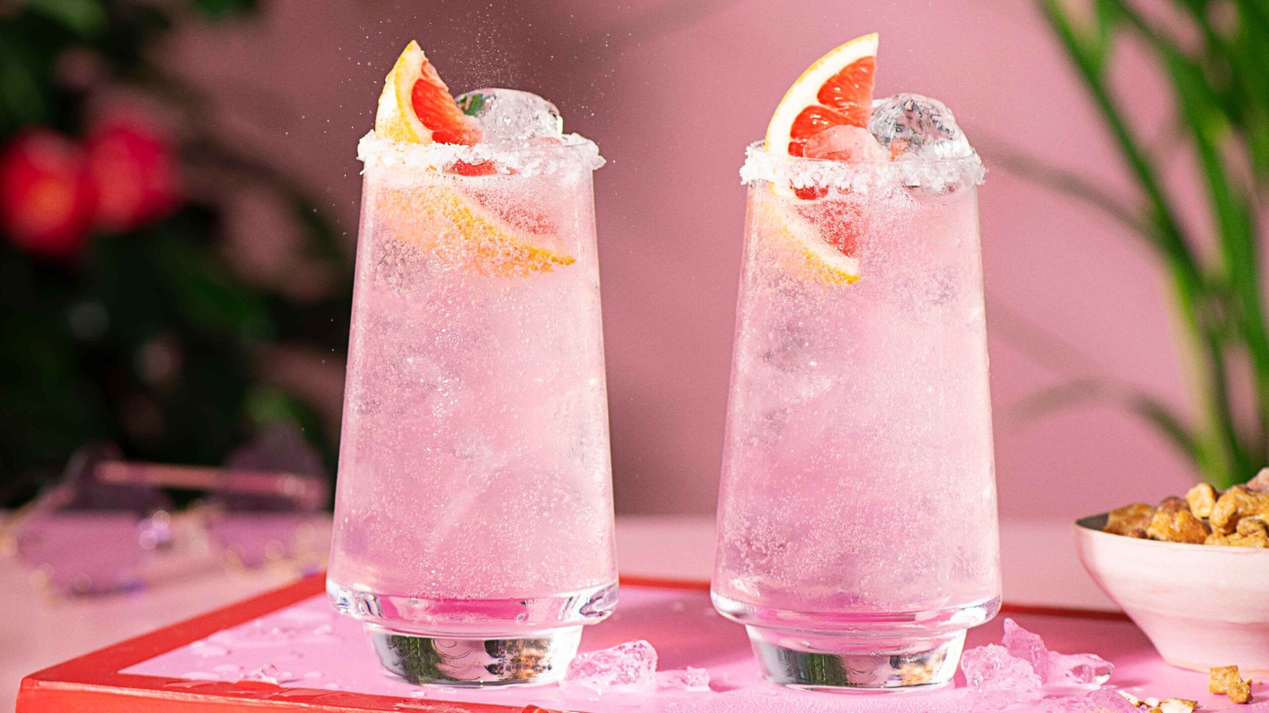 Two pink malibu Palomas in a highball glass against a pink background