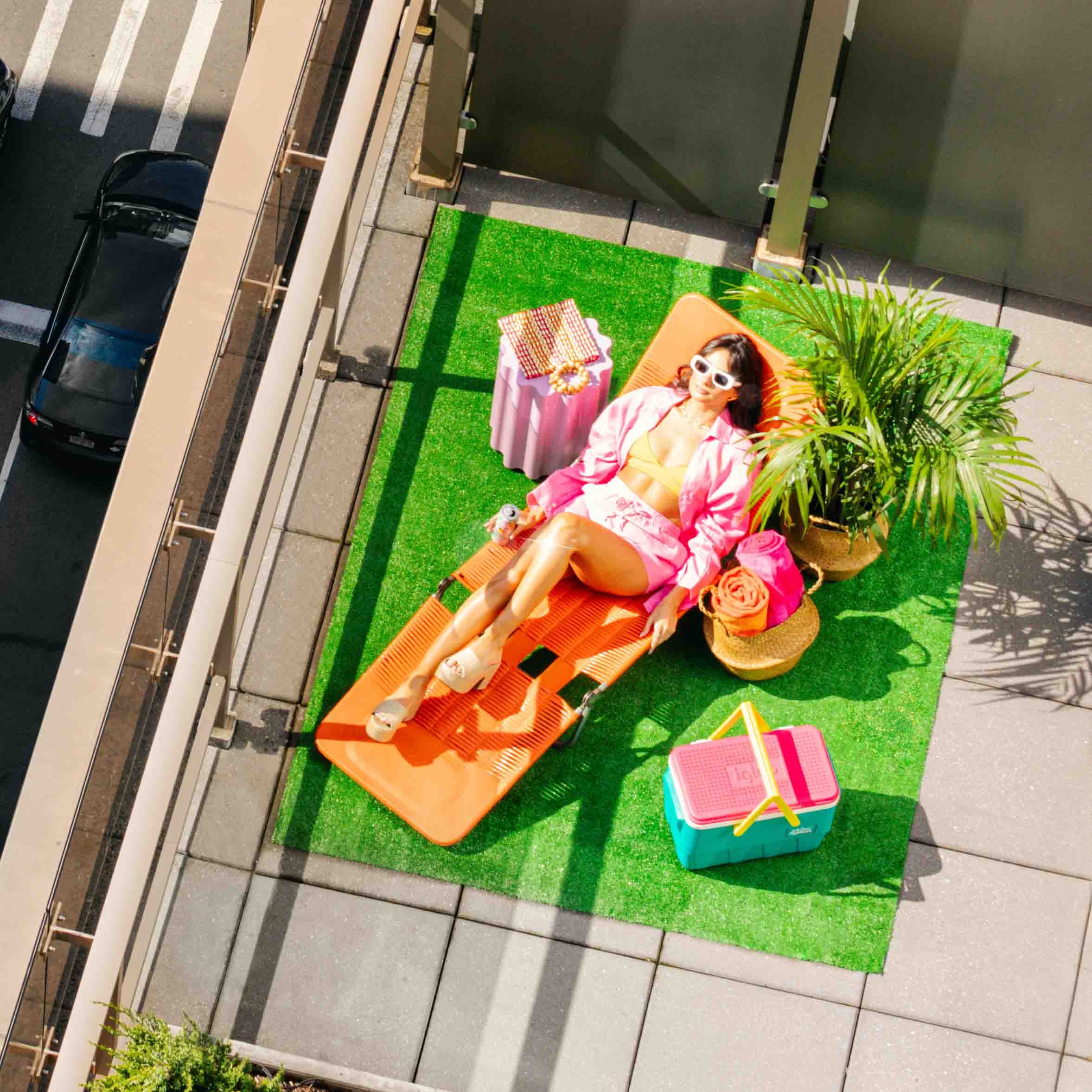 Paige sunbathing on a balcony sunbed with Malibu can
