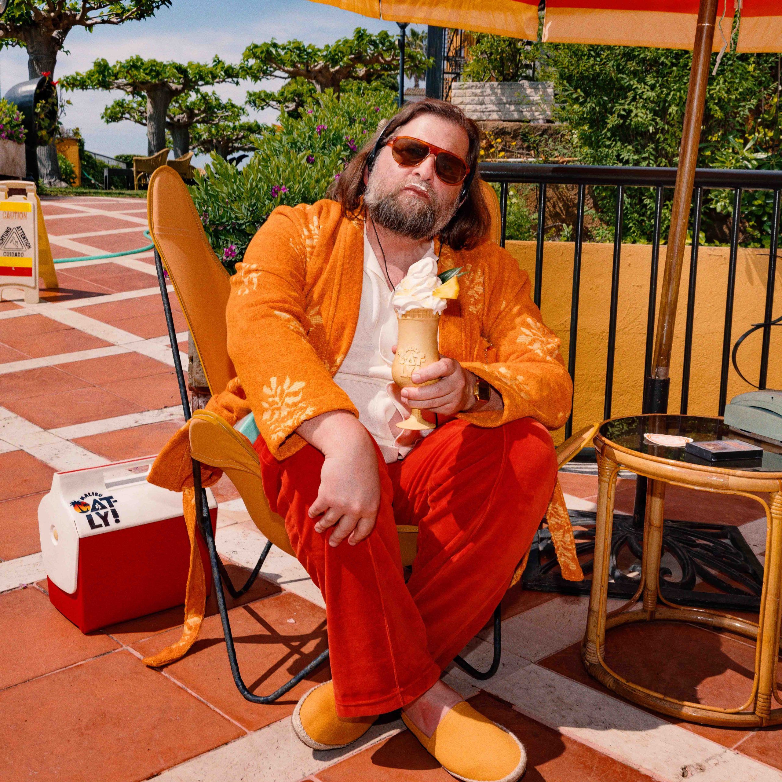 A man in a courtyard holding a Malibu x Oatly Oatlada soft serve