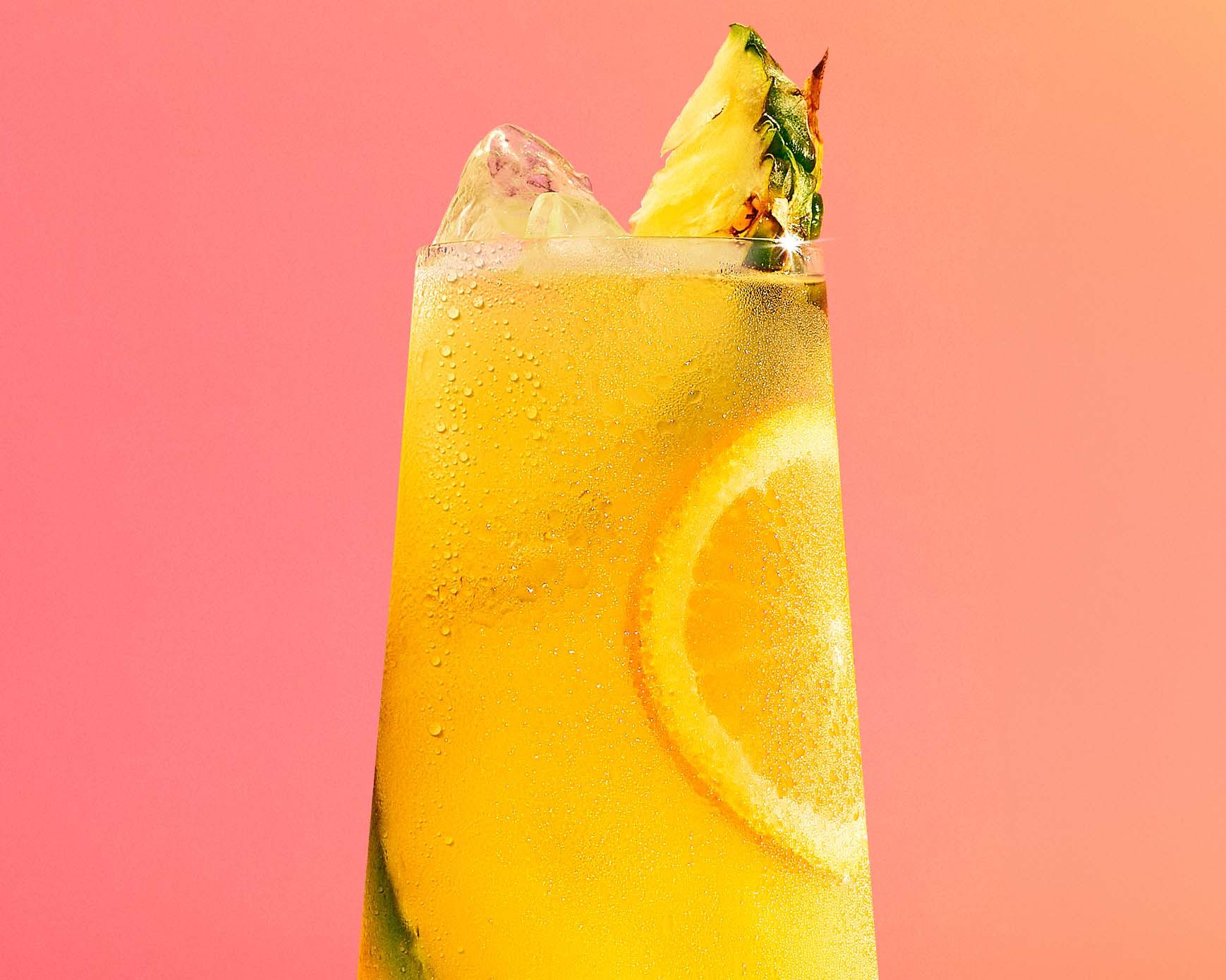 Malibu and pineapple cocktail on a coral background