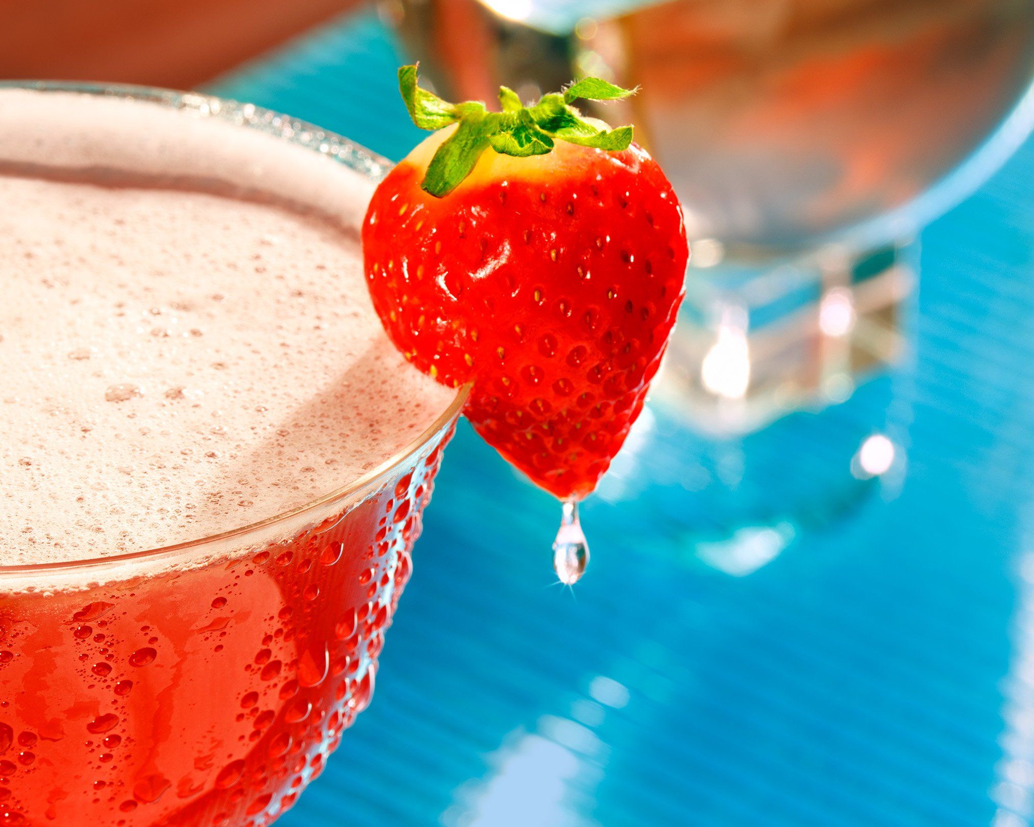Close up of a strawberry garnish on a cocktail glass filled with strawberry daiquiri