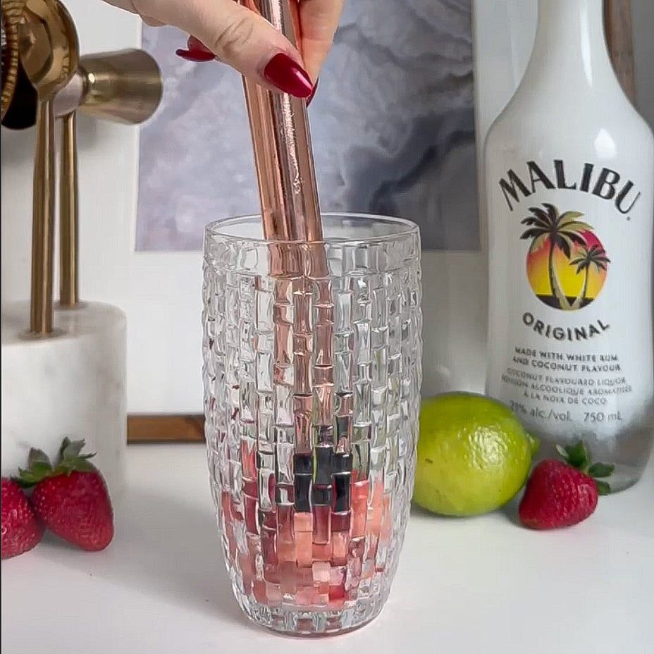Strawberries being muddled into an empty shaker.