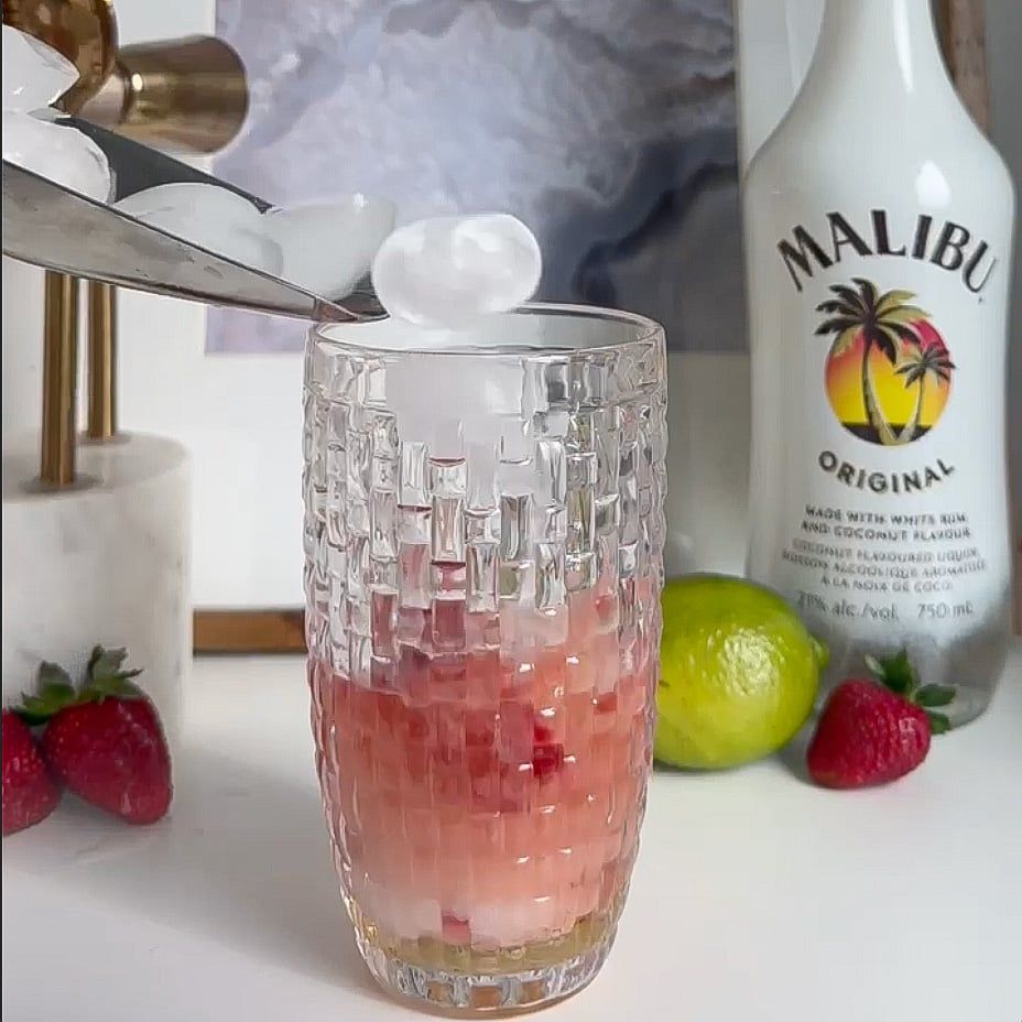 Ice being poured into a a shaker with ingredients.