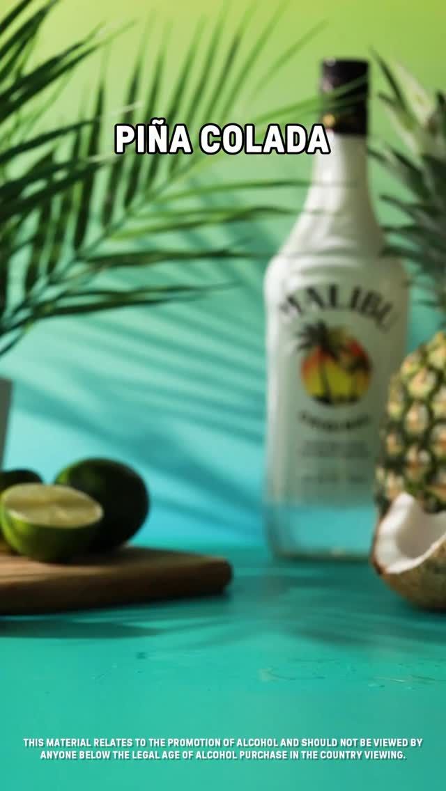 514772306_1196133079219361_7206542151858344344_n Malibu bottle with lime, coconut, pineapple, and palm leaves on a wood board, set against a vibrant tropical backdrop.
