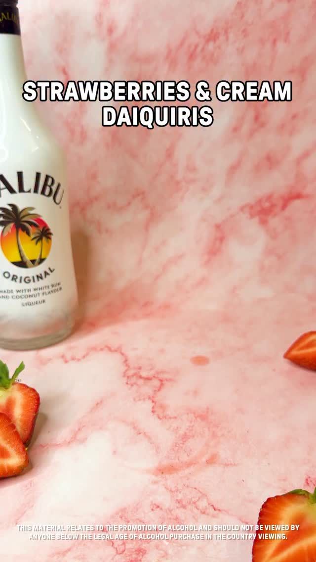 Malibu bottle with sliced strawberries on a pink marble background. Text reads: 'Strawberries & Cream Daiquiris'.
