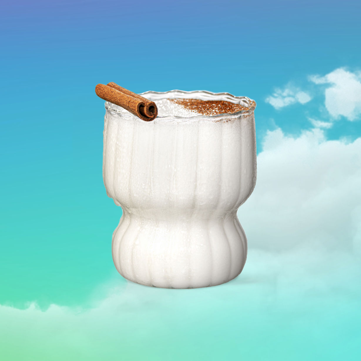 Malibu Coquito garnished with a cinnamon stick in front of a blue cloudy background