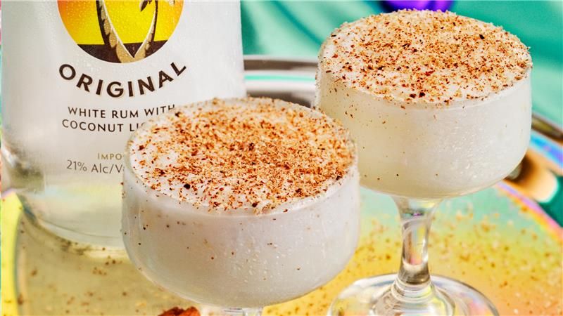 Two Malibu Coquito drink with a Malibu Original bottle behind. Garnished with cinnamon ang nutmeg