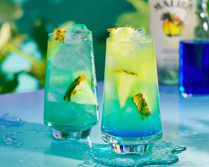 Two Malibu blue Hawaiian drinks served on ice and with pineapple