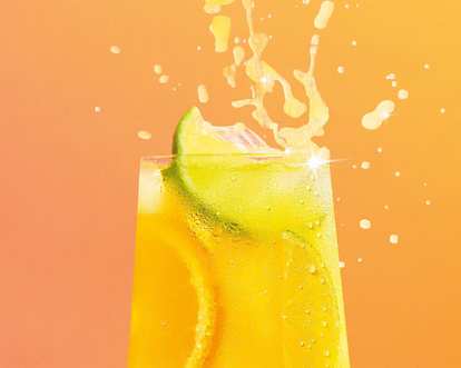 A glass of a yellow Malibu Citrus Drink with a splash and a slice of lime