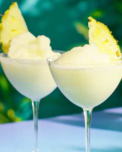 Two glasses of Frozen Malibu Pina Colada decorated with pineapple slices