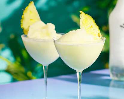 Two glasses of Frozen Malibu Pina Colada decorated with pineapple slices