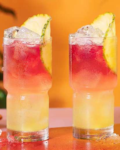Two Malibu Bay Breeze Drinks against an orange gradient backdrop