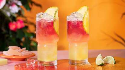 Two Malibu Bay Breeze Drinks against an orange gradient backdrop