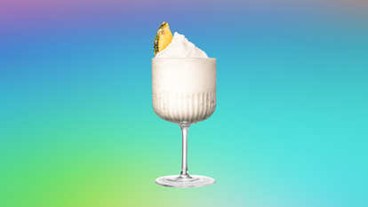 Malibu Coconut Froze — a creamy frozen coconut cocktail served in a textured goblet, topped with a pineapple wedge against a turquoise‑to‑purple gradient background.