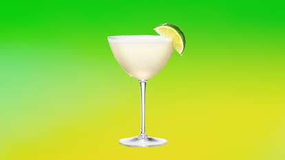 A chilled coupe glass of Malibu Daiquiri garnished with a fresh lime wedge against a bright green and yellow gradient background. The pale coconut rum cocktail glistens with condensation, evoking a crisp, tropical refreshment with a smooth, summery finish.