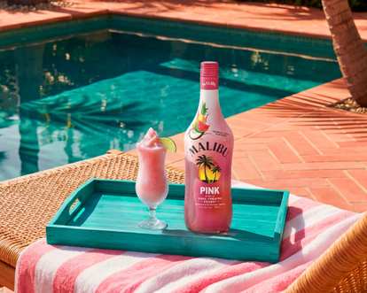 Malibu Flamingo Freeze cocktail and Malibu Pink bottle by a pool