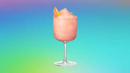 A frosted goblet filled with Malibu Froze, a pink frozen coconut rum cocktail with a smooth slushy texture and a peach slice garnish. The drink glistens with condensation against a vibrant gradient background, evoking a playful, tropical summer vibe.