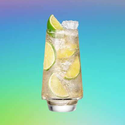 A tall glass of Malibu and ginger ale filled with ice cubes and lime slices against a vibrant gradient background. The light golden coconut rum cocktail sparkles with carbonation, evoking a fresh, tropical summer vibe.