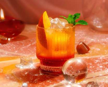 A red, yellow and orange Malibu drink decorated with a peach slice