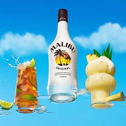 Malibu Original bottle centered between two tropical cocktails, one iced with lime splash, one creamy Piña Colada with pineapple garnish, bright blue sky and clouds creating fresh island vibe.