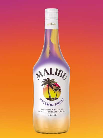 A Malibu Passion Fruit bottle displayed against a vivid orange‑to‑pink gradient background. The white bottle fades into a soft purple near the neck, featuring the signature Malibu palm logo and tropical sunset design, evoking a bright, fruity, summer feel.