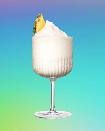 Malibu Piña Colada Slushy served blended with ice and topped with a pineapple slice for a creamy, tropical frozen cocktail.