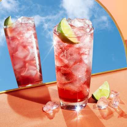 A glass of a Malibu Spring drink in front of a mirror.
