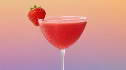Malibu Strawberry Daiquiri cocktail in a coupe glass with bright red drink and a fresh strawberry garnish, condensation on the glass against a soft gradient background of peach and lavender tones.