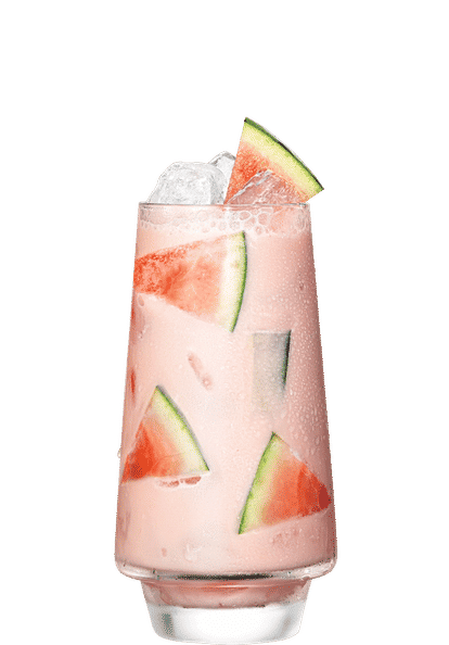 Malibu Watermelon Colada cocktail in a tall glass with light pink creamy drink, ice cubes, and triangular watermelon slices, condensation on the glass, isolated on a white background.