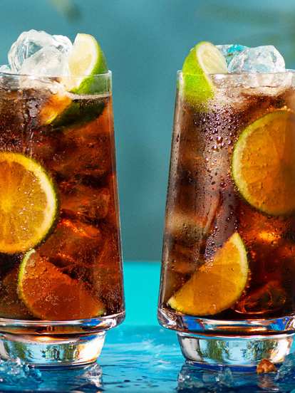 Two Malibu and cola drinks on ice decorated with lime