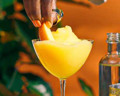 One yellow Malibu Frozen Mango Daiquiri and a hand putting a slice of mango