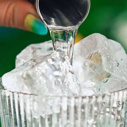 Close up of Malibu being poured into a glass with ice from a jigger