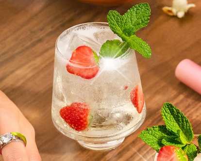 A glass of Malibu Strawberry Spritz decorated with lime and strawberries
