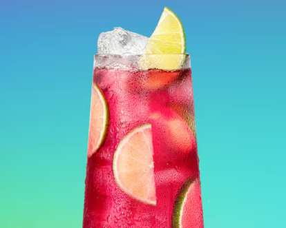 Malibu Cranberry Lemonade cocktail in a tall glass with bright pink‑red drink, ice cubes, and lime slices, condensation on glass, set against a smooth blue‑to‑green gradient background for a fresh tropical look.