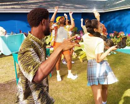 People dancing in a garden, holding cans of Malibu in their hands