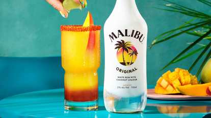 Malibu  Mangonada with chili spice and Malibu Original rum next to a Malibu Bottle and Mangos