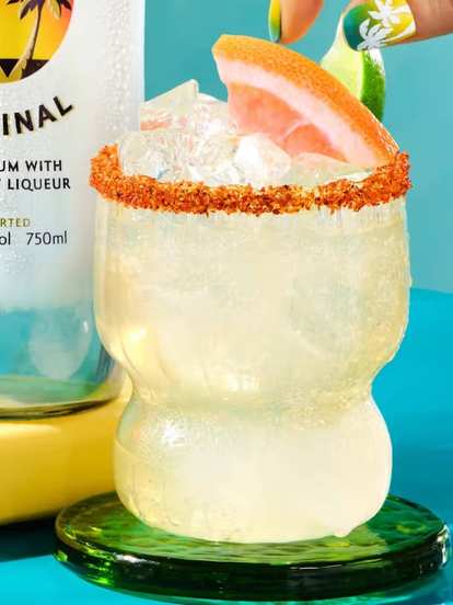 Malibu  Paloma de Coco served in a curvy glass with ice, chili‑salt rim, and grapefruit wedge garnish.