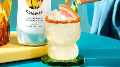 Malibu  Paloma de Coco served in a curvy glass with ice, chili‑salt rim, and grapefruit wedge garnish.